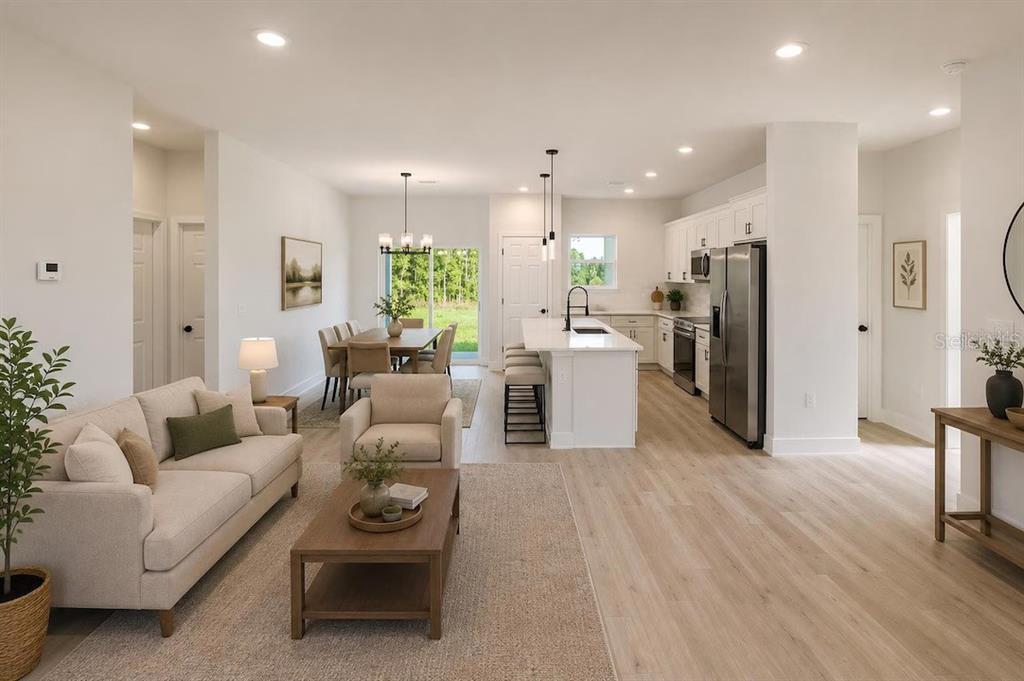 An open-concept living room, dining area, and kitchen with white cabinetry and light wood flooring — 3286 W CRANDON DRIVE, CITRUS SPRINGS, FL