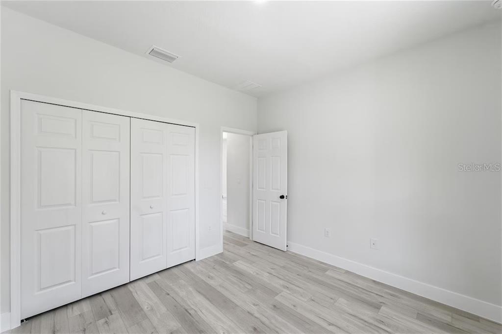 An empty bedroom features light gray wood-look flooring, white walls, a closet, and a doorway — 3286 W CRANDON DRIVE, CITRUS SPRINGS, FL
