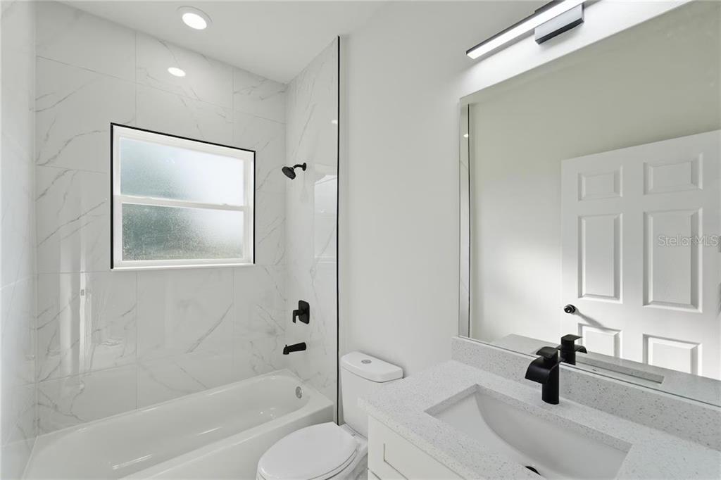 A modern bathroom features a white vanity, a toilet, and a tiled tub-shower combination — 3286 W CRANDON DRIVE, CITRUS SPRINGS, FL