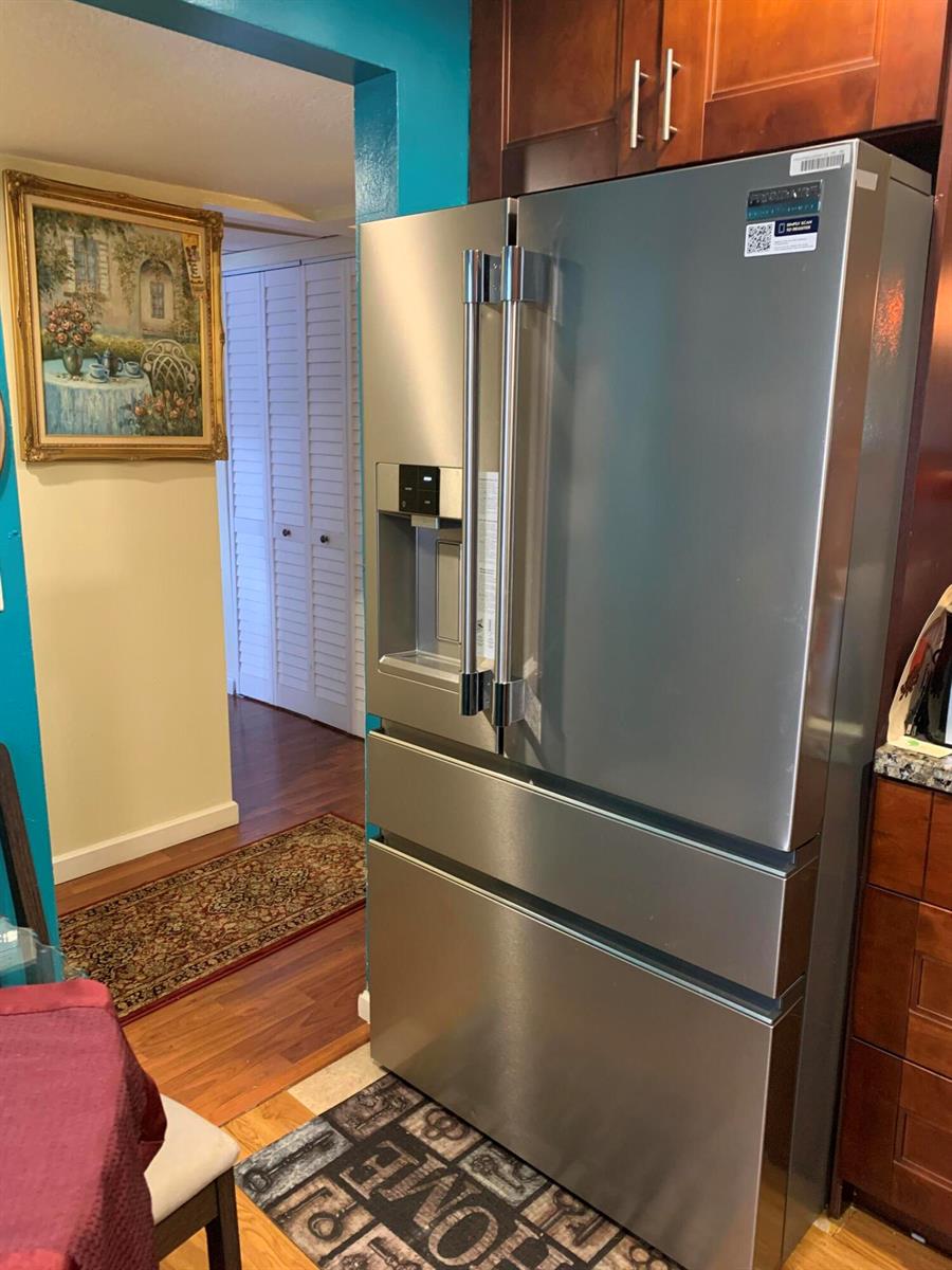 A stainless steel French door refrigerator stands in a kitchen with dark wood cabinets — 7887 Golf Cir Drive # 212, Margate FL 33063, MARGATE, FL