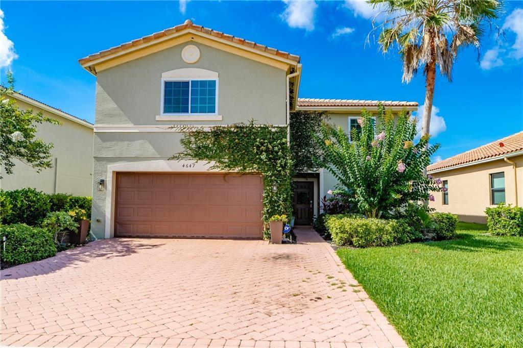 A two-story house with a tan stucco exterior, a two-car garage, and a paved driveway — VERO BEACH, FL