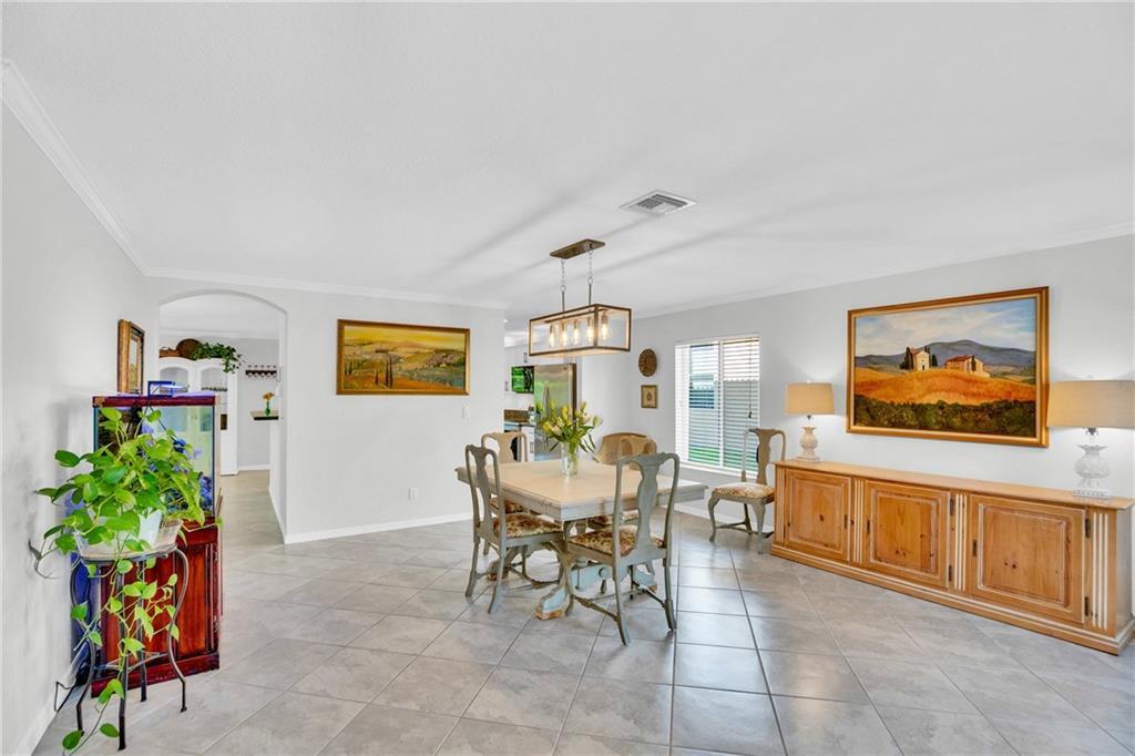 A dining room features tile flooring, a wooden table with chairs, and a sideboard cabinet — VERO BEACH, FL