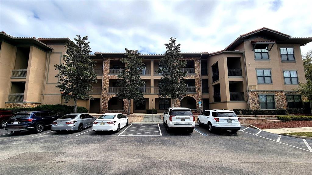 A multi-story apartment building with a stone facade and a parking lot in front — 914 CHARO PARKWAY UNIT 123, DAVENPORT, FL