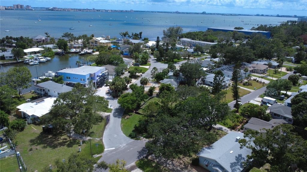 An aerial view shows a coastal neighborhood with houses, a canal, and a large bay — 4725 TRADE WINDS DRIVE S, GULFPORT, FL