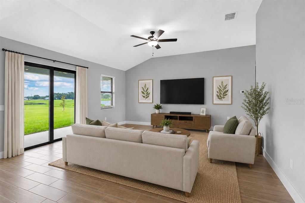 A living room features a beige sofa, a television, and sliding doors overlooking a grassy field — 2405 GALLAGHER ROAD, DOVER, FL
