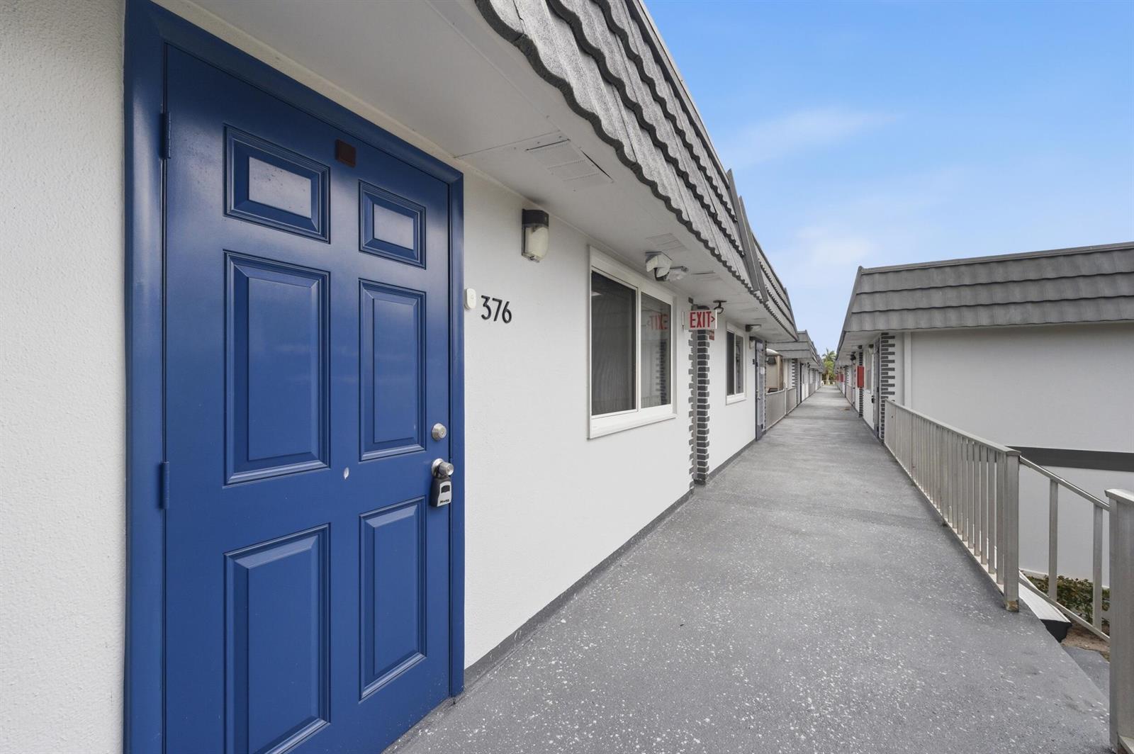 An exterior view of a motel walkway with a blue door labeled 376 — 376 Saxony H, Delray Beach FL 33446, DELRAY BEACH, FL