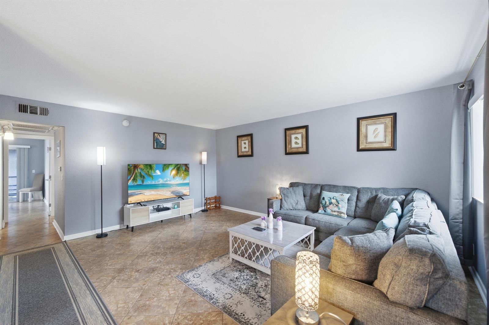 A living room features gray walls, tile flooring, a sectional sofa, and a television console — 376 Saxony H, Delray Beach FL 33446, DELRAY BEACH, FL