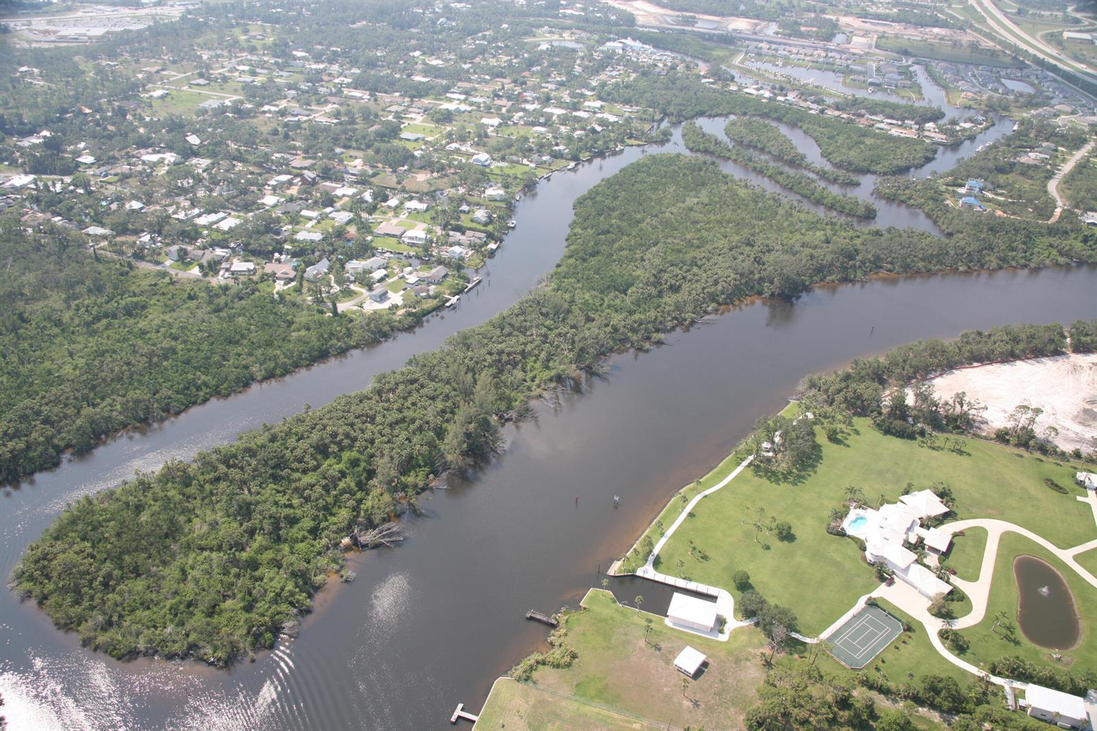 Aerial view of a river winding through a residential neighborhood with a large waterfront estate — 0 Blue Water Way, Stuart FL 34997, STUART, FL