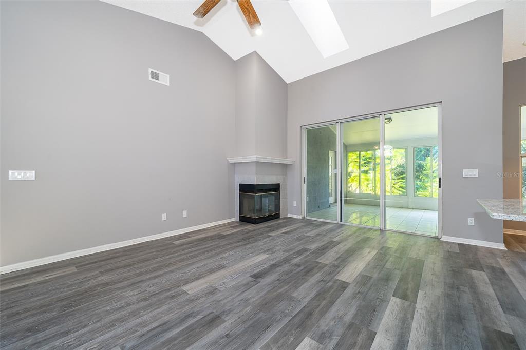 A living room with gray walls, wood-look flooring, a corner fireplace, and sliding glass doors — 7304 HIGH LAKE DRIVE, ORLANDO, FL
