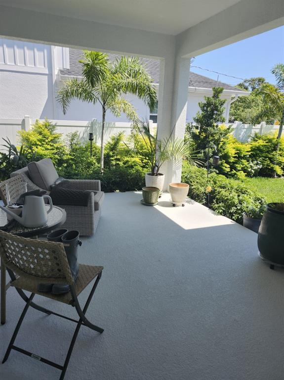 A covered patio features gray concrete flooring, outdoor furniture, potted plants, and a fenced yard — 4810 EMERSON AVENUE S, ST PETERSBURG, FL