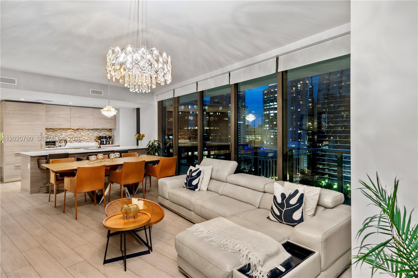 A modern open-concept living and dining area features a large sectional sofa and city views — 1300 S Miami Ave # 1405, Miami FL 33130, MIAMI, FL