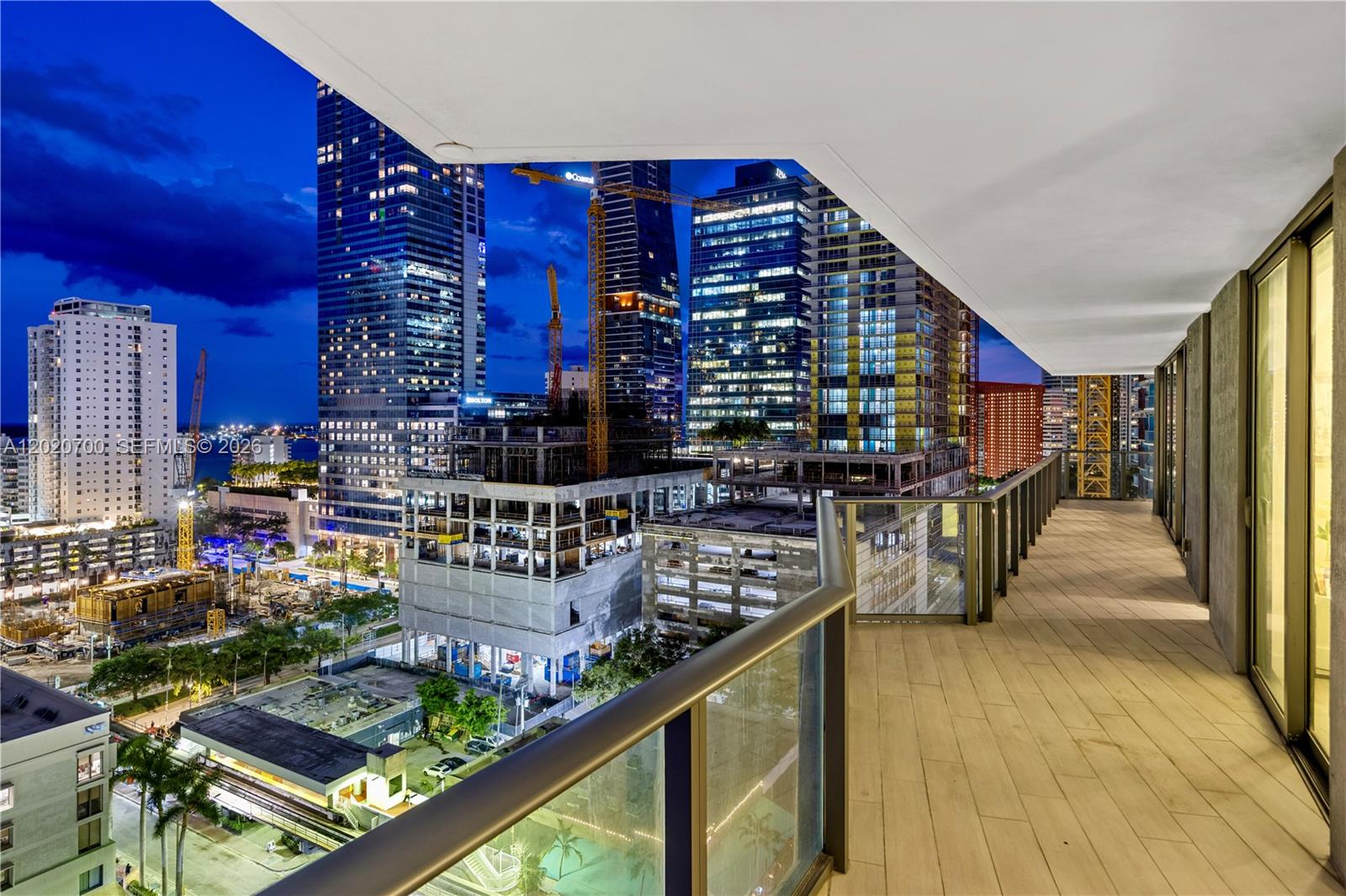 A balcony with wood-look tile flooring overlooks a city skyline at night — 1300 S Miami Ave # 1405, Miami FL 33130, MIAMI, FL