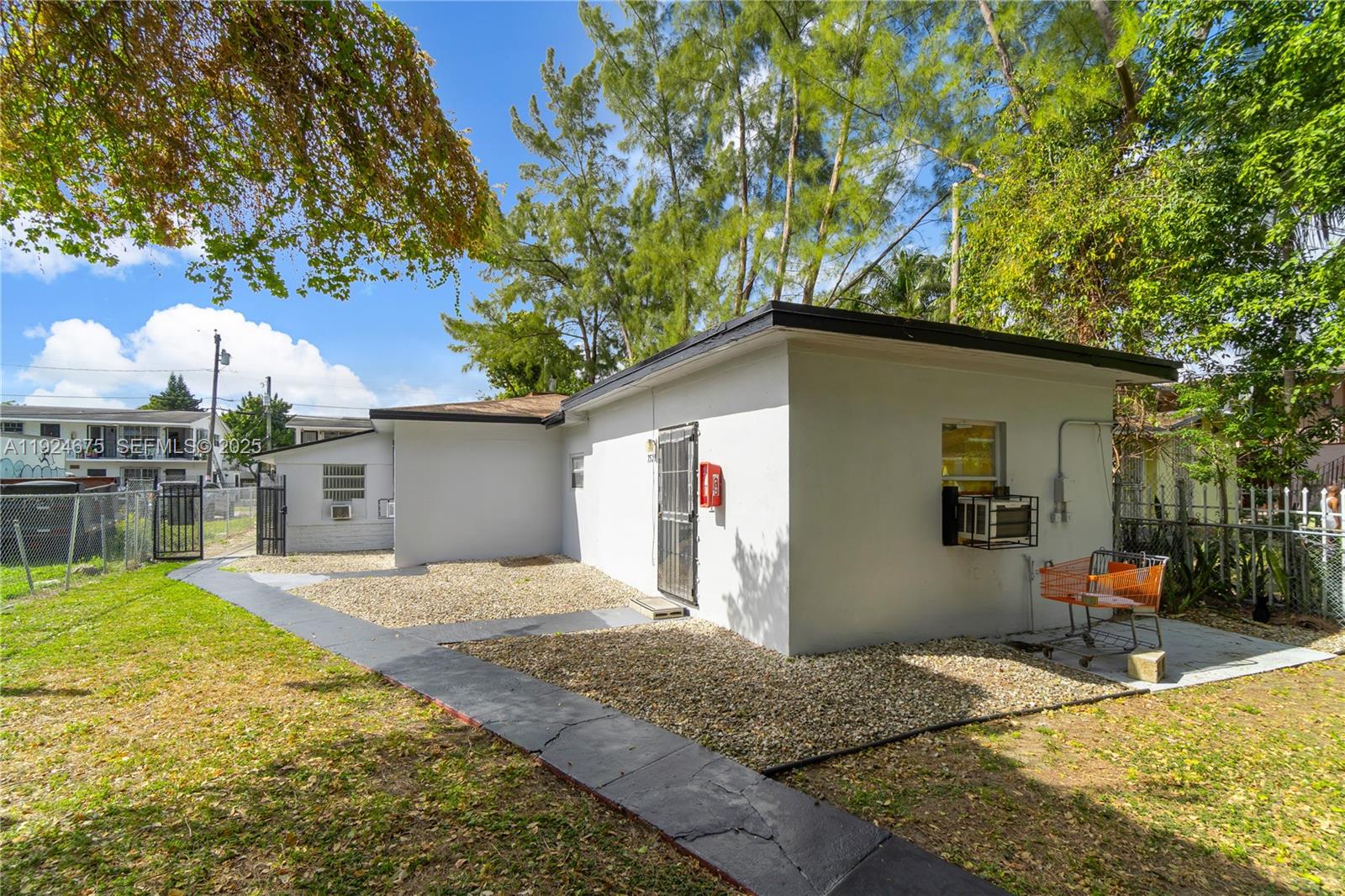 The exterior of a white, flat-roofed building features a gravel yard and a concrete walkway — 7525 NE Miami Ct, Miami FL 33138, MIAMI, FL