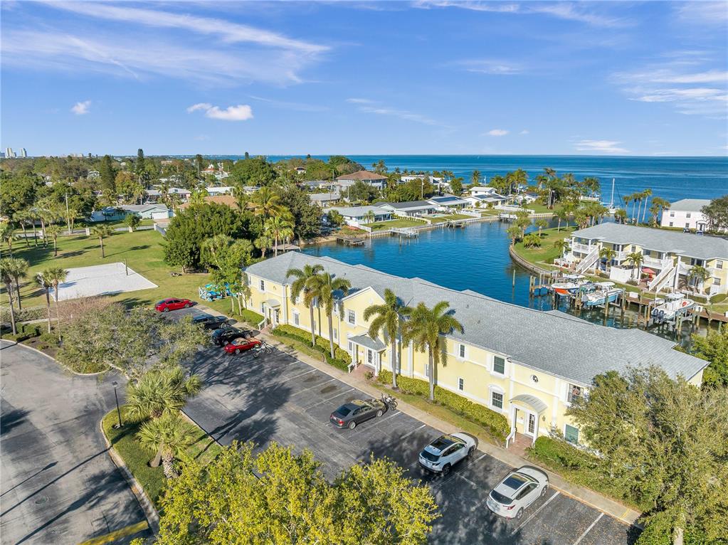 An aerial view shows a yellow multi-unit waterfront building with boat slips along a canal — 4728 BEACH DRIVE SE UNIT A, ST PETERSBURG, FL