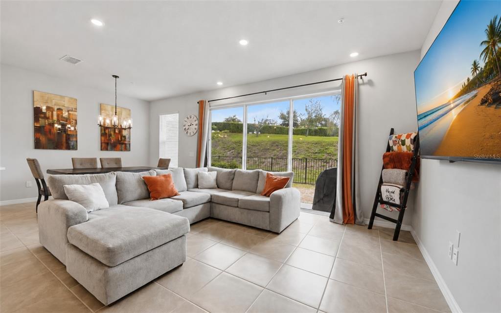 A living room with a gray sectional sofa, tile floors, and a large sliding glass door — 547 ASTERA WINDS LANE, LAKE MARY, FL