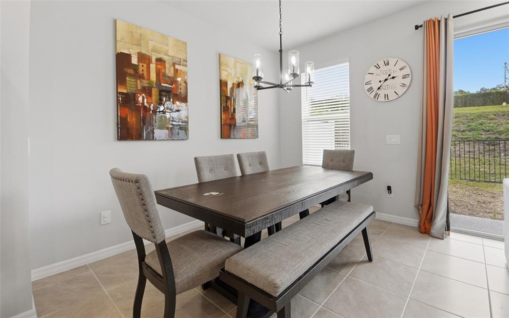 A dining room features a dark wood table, upholstered chairs, a bench, and wall art — 547 ASTERA WINDS LANE, LAKE MARY, FL