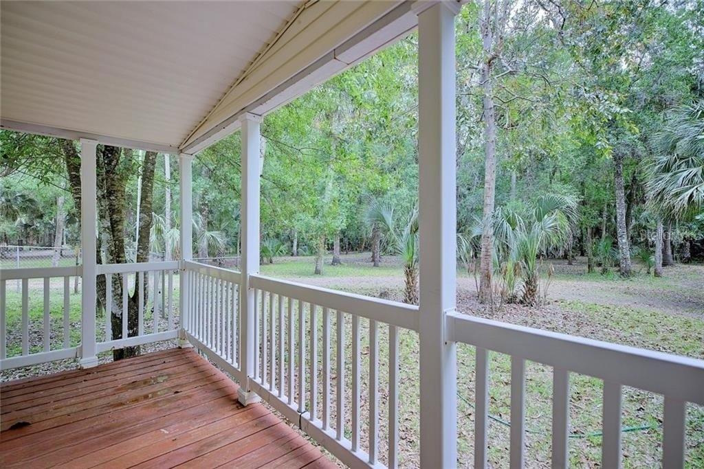 A covered wooden porch overlooks a wooded backyard with trees and palm plants — 2500 ARBUCKLE SHORES ROAD, FROSTPROOF, FL
