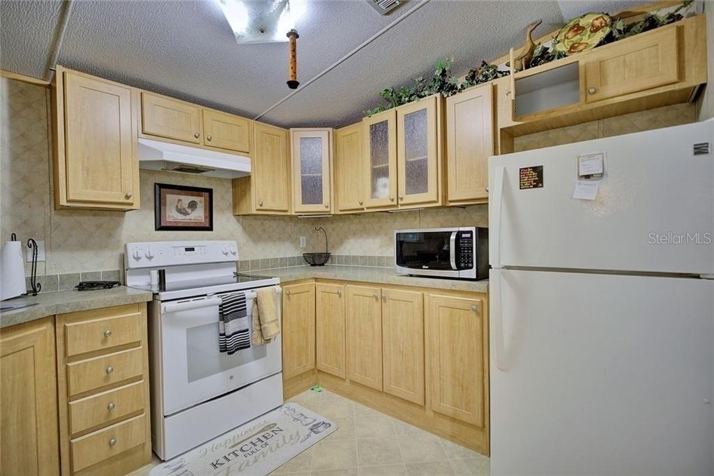 A kitchen features light wood cabinets, white appliances, and a patterned floor — 2500 ARBUCKLE SHORES ROAD, FROSTPROOF, FL