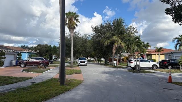 A residential street scene featuring parked cars, palm trees, and houses under a blue sky — 774 NW 16th Pl, Pompano Beach FL 33060, POMPANO BEACH, FL