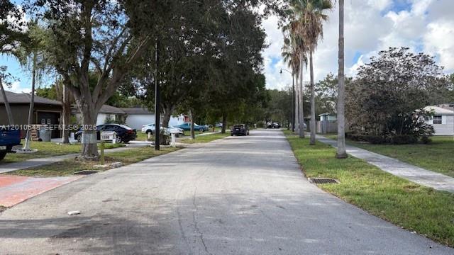 A residential street features houses, parked cars, mature trees, and palm trees under a sky — 774 NW 16th Pl, Pompano Beach FL 33060, POMPANO BEACH, FL