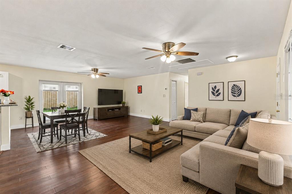 A living room and dining area with wood-look flooring, a sectional sofa, and ceiling fans — 3822 RAVENNA DRIVE, VALRICO, FL