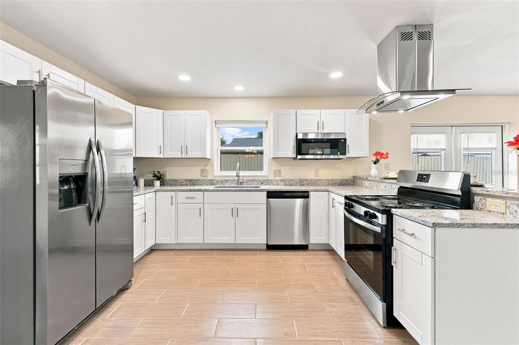 A kitchen with white cabinets, granite countertops, stainless steel appliances, and light-colored tile flooring — 3822 RAVENNA DRIVE, VALRICO, FL