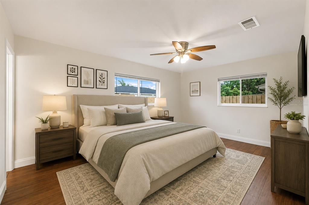 A bedroom with a king bed, wood flooring, and two windows in a neutral room — 3822 RAVENNA DRIVE, VALRICO, FL
