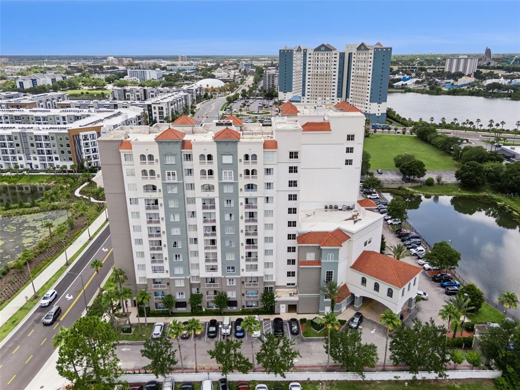 An aerial view shows a multi-story apartment building with a red-tiled roof and parking lot — 7395 UNIVERSAL BOULEVARD UNIT 403, ORLANDO, FL
