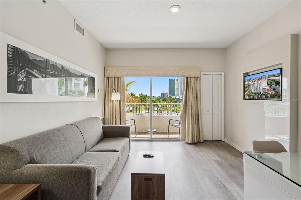 A living room features a gray sofa, a coffee table, and a sliding door to a balcony — 7395 UNIVERSAL BOULEVARD UNIT 403, ORLANDO, FL