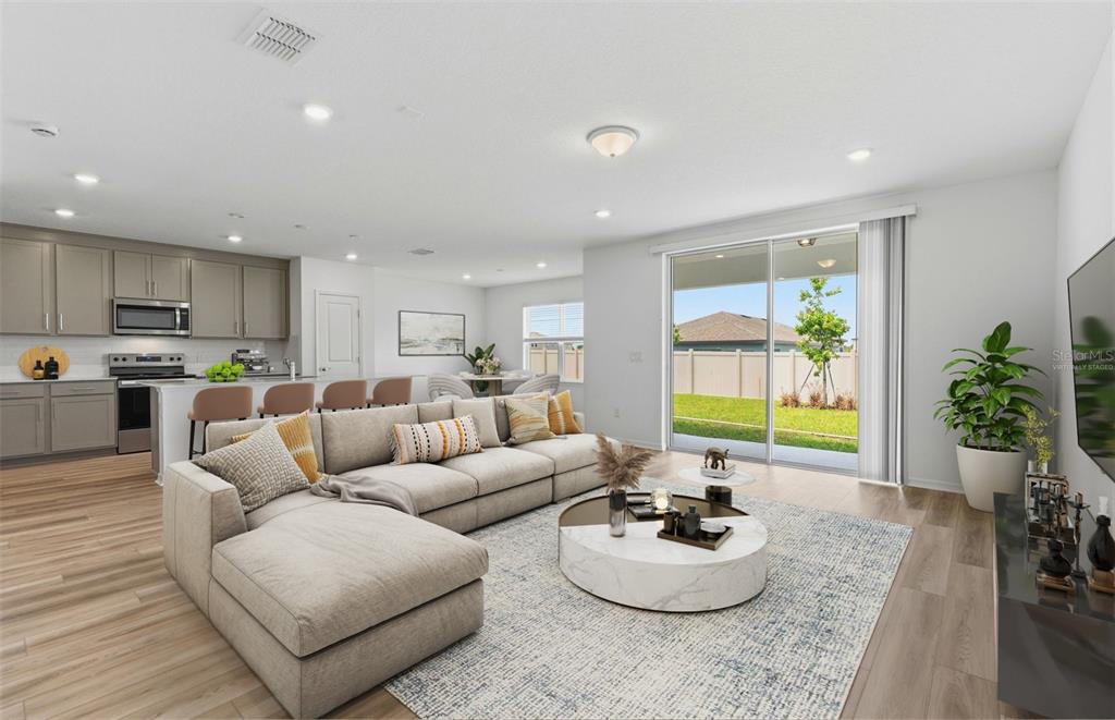A modern open-concept living room and kitchen with a sectional sofa and sliding glass doors — 1448 HAMILTON WAY, LAKE ALFRED, FL