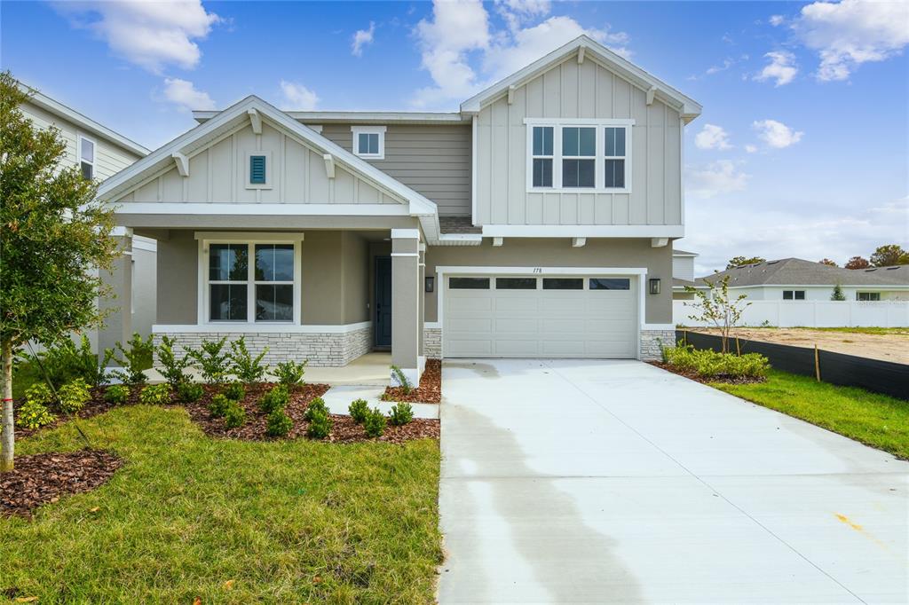 A two-story suburban house features a front porch, a two-car garage, and stone accents — 178 BLUE STAR COURT, TAVARES, FL