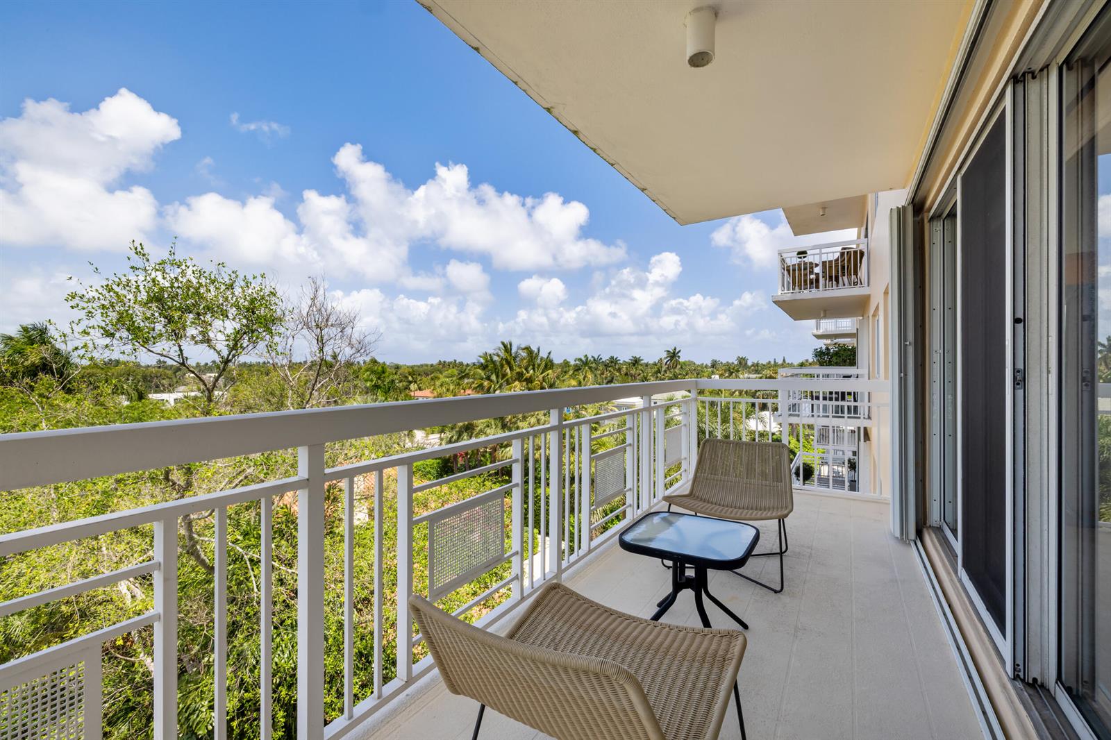 A balcony with two wicker chairs, a small glass table, and a white metal railing — 250 Bradley Place # 606, Palm Beach FL 33480, PALM BEACH, FL