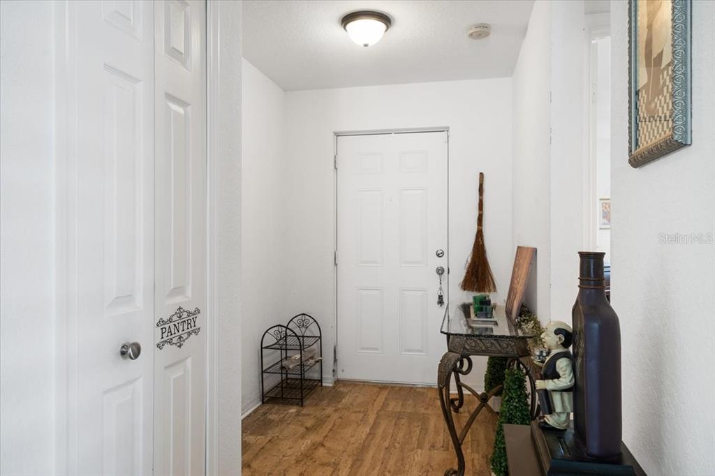 This entryway features a white front door, a pantry closet, and wood-look flooring — 12 PALO ALTO LANE, PORT ST LUCIE, FL