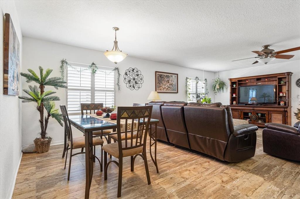 A dining area with a glass-top table sits adjacent to a living room with leather furniture — 12 PALO ALTO LANE, PORT ST LUCIE, FL