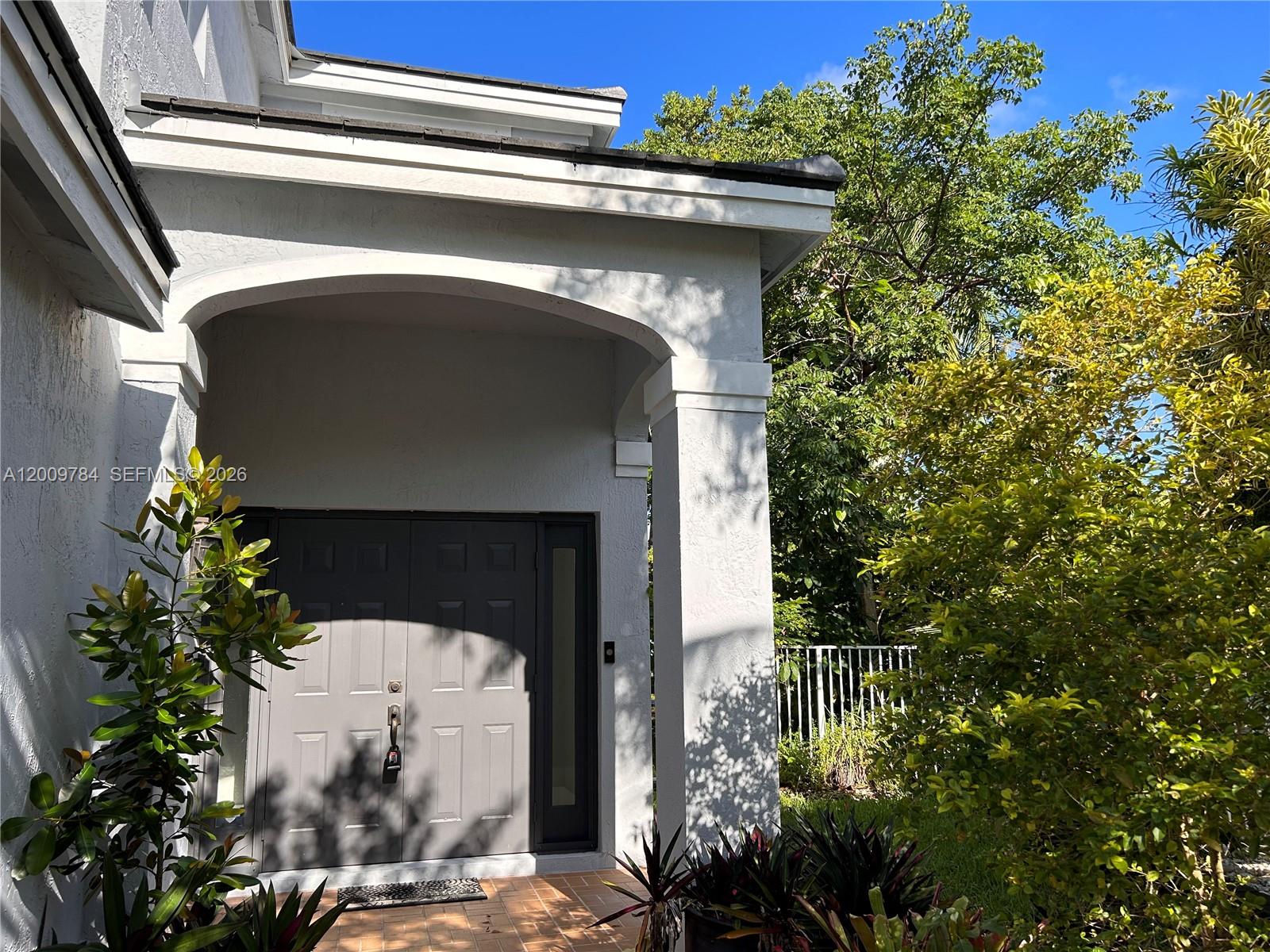 A gray double front door is set under a covered entryway with a tiled porch — 980 Golden Cane Dr, Weston FL 33327, WESTON, FL