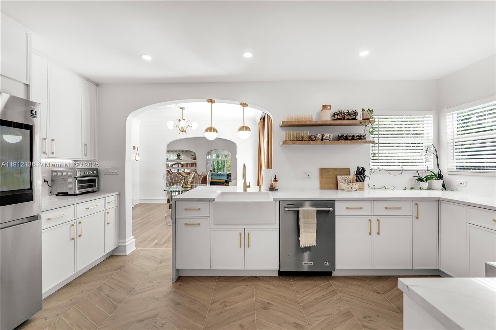 A bright kitchen features white cabinets, a farmhouse sink, and light wood herringbone flooring — 1601 Washington St, Hollywood FL 33020, HOLLYWOOD, FL