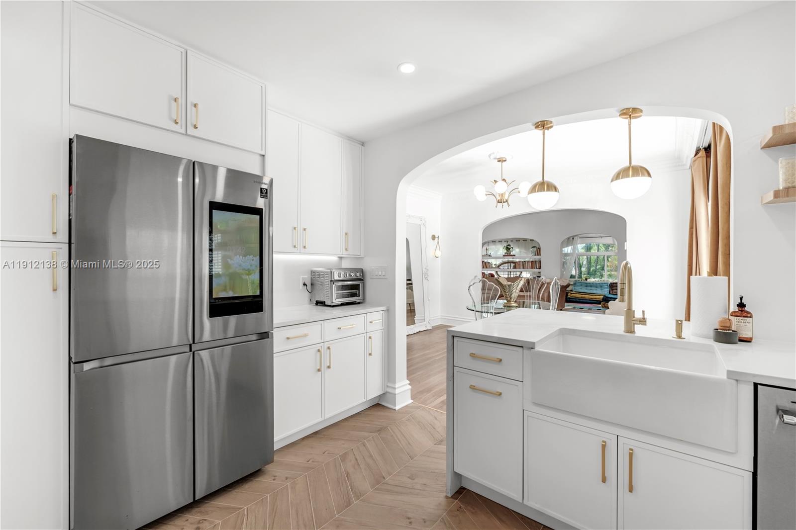 A modern white kitchen features stainless steel appliances, gold hardware, and a farmhouse sink — 1601 Washington St, Hollywood FL 33020, HOLLYWOOD, FL