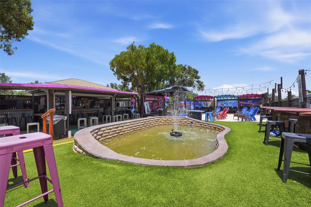 An outdoor patio area features a central fountain, artificial turf, and a covered bar — 8744 GALL BLVD, ZEPHYRHILLS, FL
