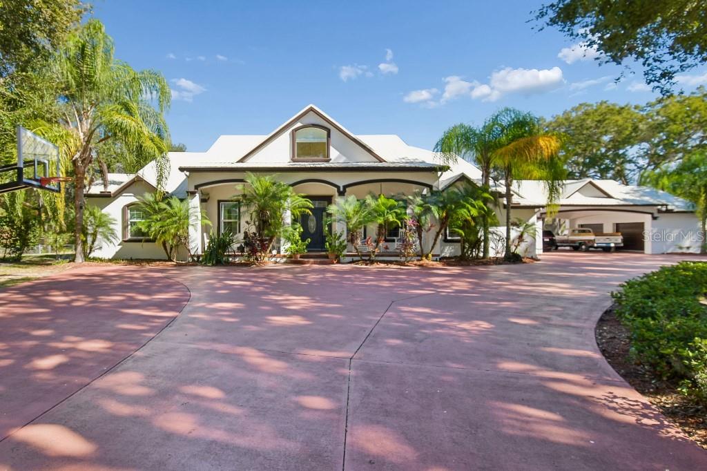 A single-story house with a white exterior, arched porch, and a large red concrete driveway — 3302 JAP TUCKER ROAD, PLANT CITY, FL