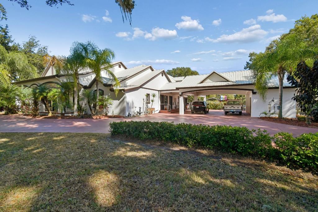 A large, single-story house with a metal roof, a porte-cochère, and a paved driveway — 3302 JAP TUCKER ROAD, PLANT CITY, FL