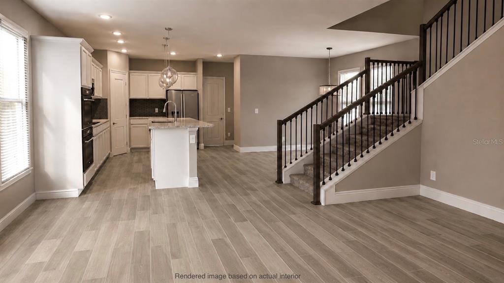 This rendering shows a kitchen with white cabinets and an island next to a staircase — 10301 AUSTRINA OAK LOOP, WINTER GARDEN, FL