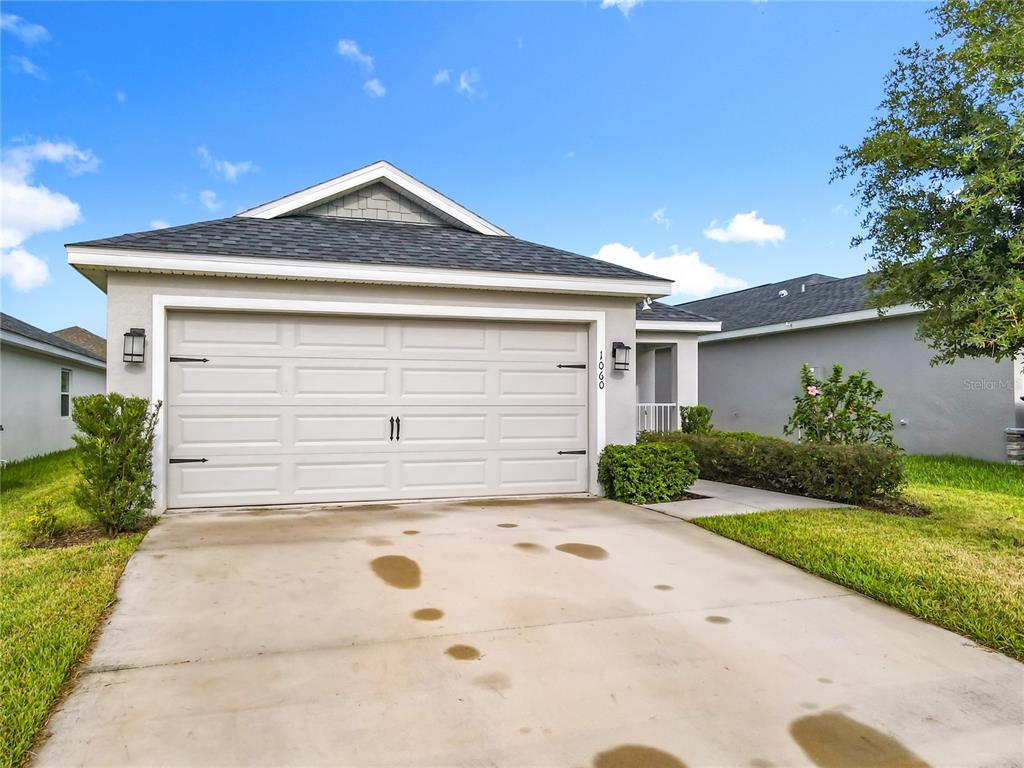 A single-story house features a two-car garage, a concrete driveway, and a landscaped front yard — 1060 CASCADE DRIVE, DAVENPORT, FL