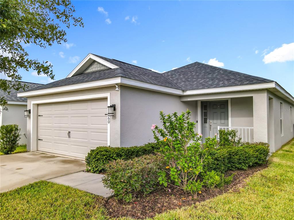 A single-story house with a gray exterior, a two-car garage, and a landscaped front yard — 1060 CASCADE DRIVE, DAVENPORT, FL