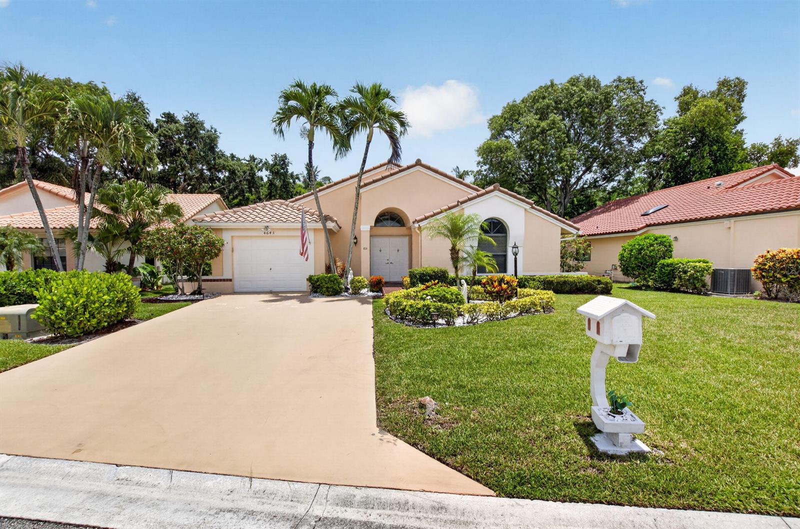 A single-story peach-colored house features a white garage, a paved driveway, and palm trees — 4643 Sextant Circle, Boynton Beach FL 33436, BOYNTON BEACH, FL
