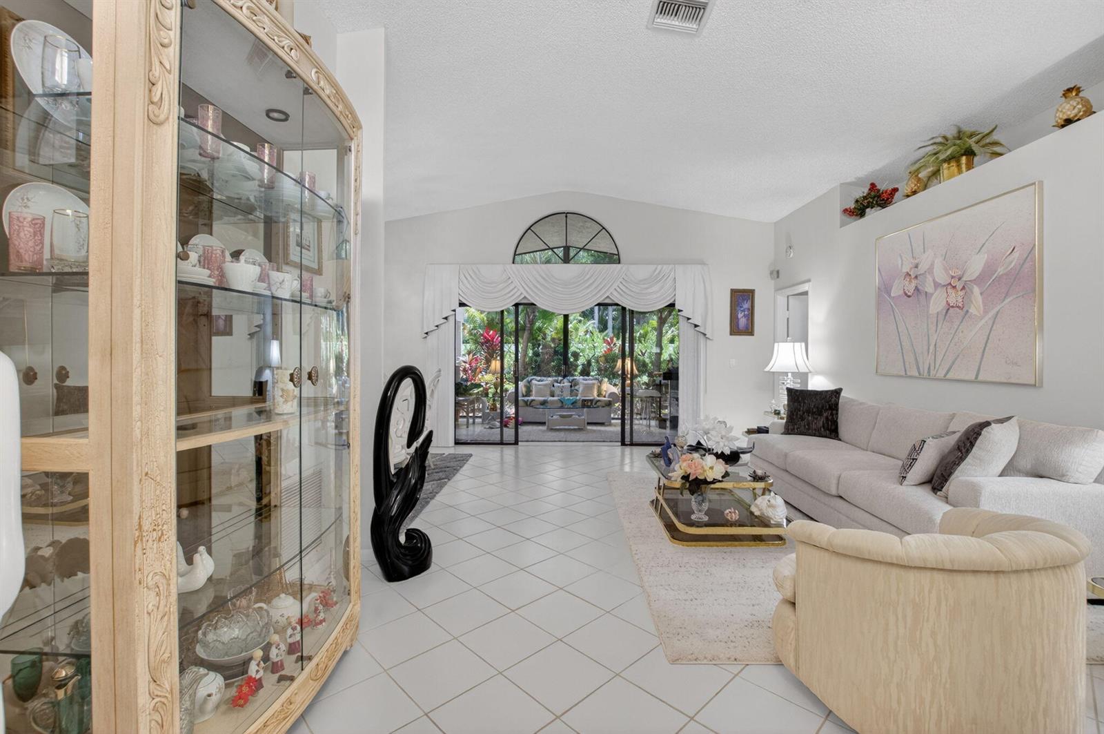A living room with tile floors, a glass display cabinet, and sliding doors to a patio — 4643 Sextant Circle, Boynton Beach FL 33436, BOYNTON BEACH, FL