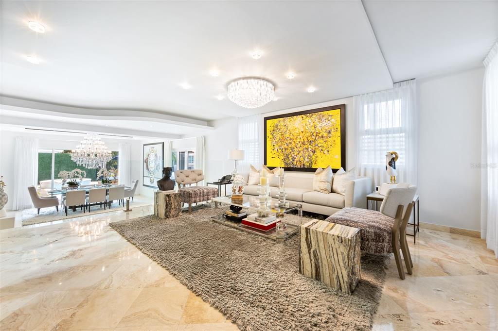 A bright, open-concept living and dining area features marble floors, a large yellow abstract painting — Calle Boulevard URB. LOS ÁRBOLES DE MONTEHIEDRA, SAN JUAN, PR