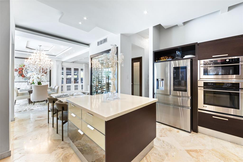 A modern kitchen features a central island, stainless steel appliances, and marble flooring — Calle Boulevard URB. LOS ÁRBOLES DE MONTEHIEDRA, SAN JUAN, PR