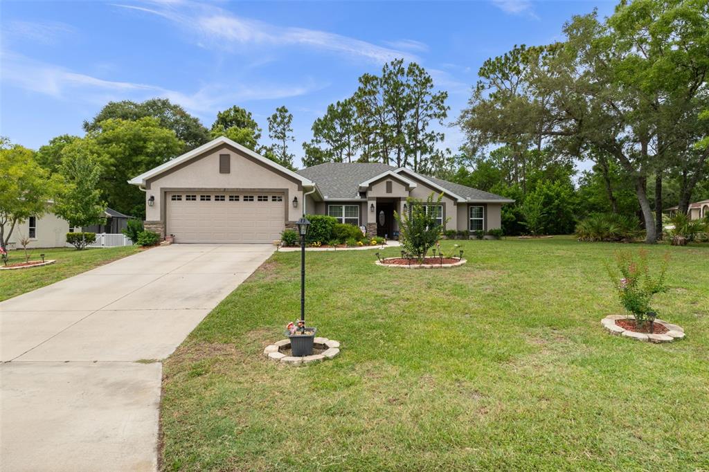 A single-story house with a beige exterior, a two-car garage, and a large front lawn — 2 BALSAM DRIVE, HOMOSASSA, FL