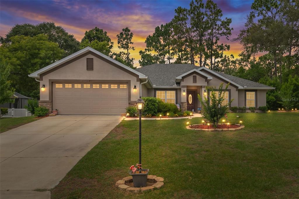 A single-story house with a two-car garage, stone accents, and a landscaped front lawn — 2 BALSAM DRIVE, HOMOSASSA, FL