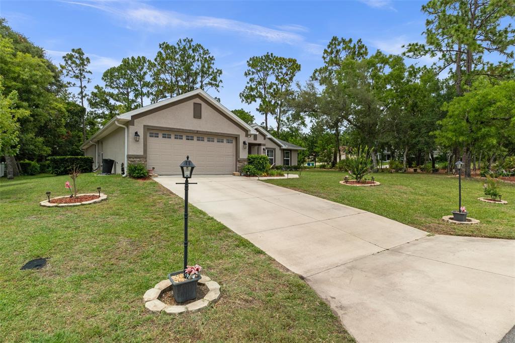 A single-story house with a beige stucco exterior and a two-car garage — 2 BALSAM DRIVE, HOMOSASSA, FL